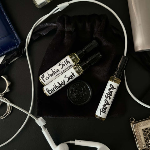 Three fragrance samples in glass bottles: Birthday Suit, Pistachio Silk, Tramp Stamp, in a black pouch.