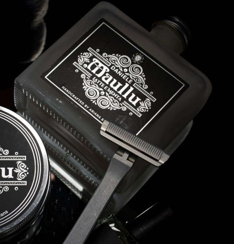 Daniele Maullu aftershave splash with luxury shaving soap and grooming tools on a dark background.