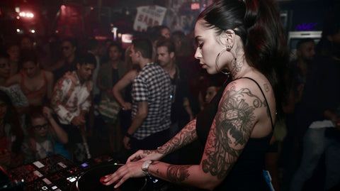 DJ with tattoos at a concert with a crowd in the background
